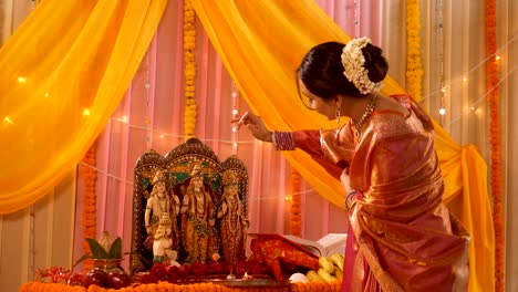 indian woman applying tika to hindu god idols - rama, lakshmana, hanuman, sita in mandir