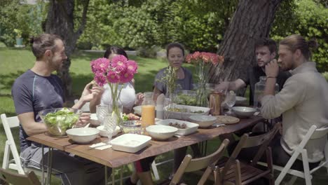 friends gathering around table in backyard