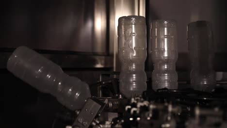 upside down plastic bottles being sterilized and washed before being filled with vinegar at a factory