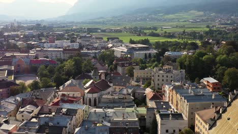 aerial footage of mountain town in austria witha river, colorful houses, towers, summer scenery, austrian alps from above, austria, europe