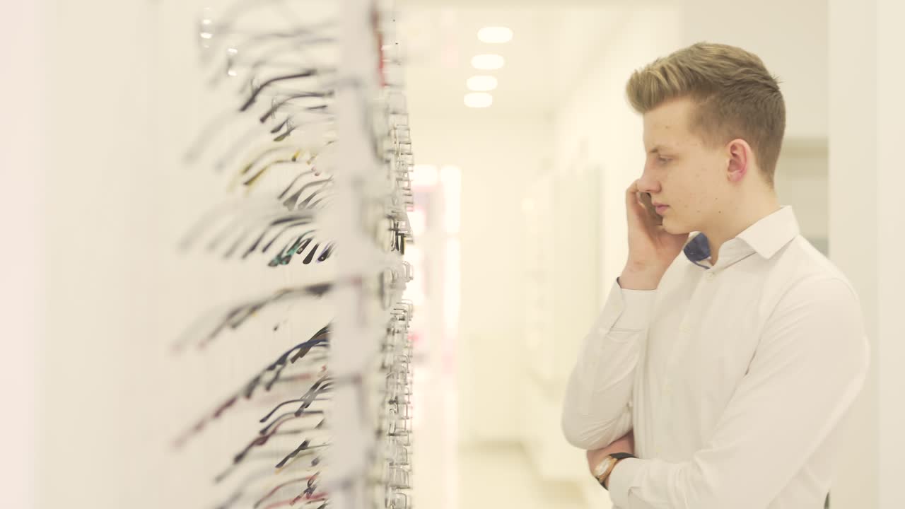 Blonde guy searching for a pair of eyeglasses while speaking on the phone