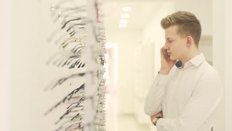 blonde guy searching for a pair of eyeglasses while speaking on the phone