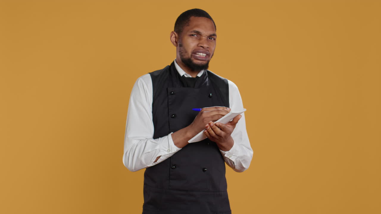 camarero experto con delantal toma las órdenes de comida de los clientes en un cuaderno