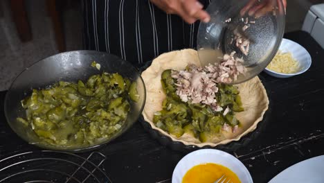 female baker mixing sliced zucchini and meat in a pie crust