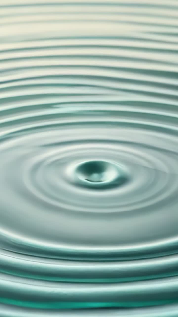 Vertical video: Creating concentric ripples expanding from droplet hitting water surface in tank