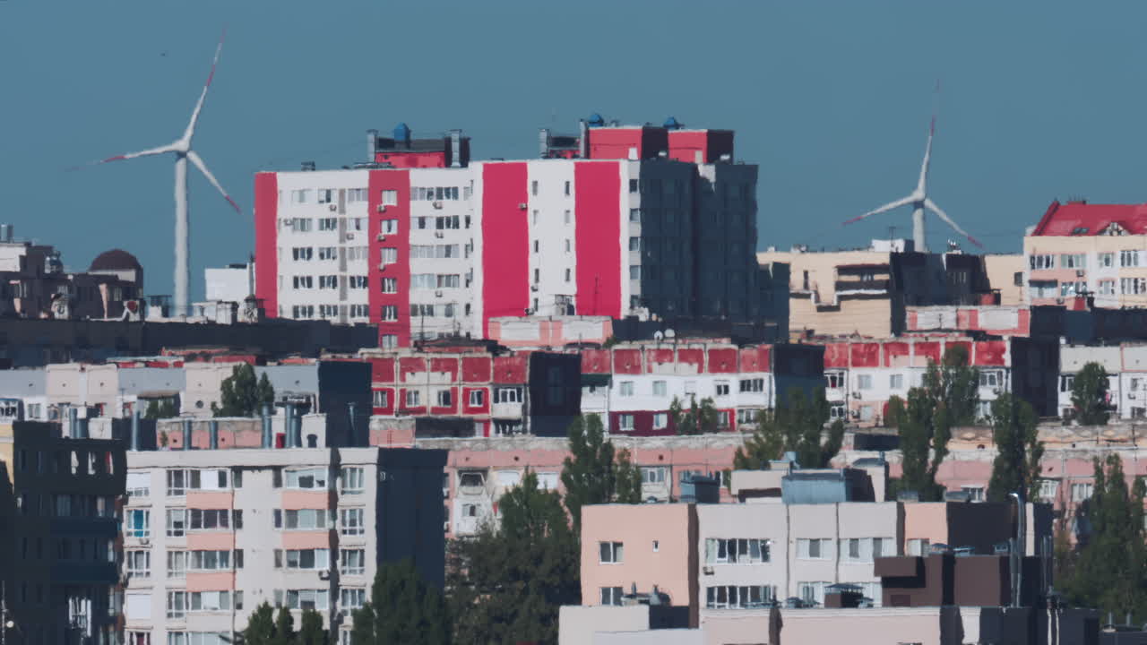 View of an urban skyline with wind turbines in the background