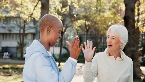 a group of three senior citizens celebrate together outdoors in a park.