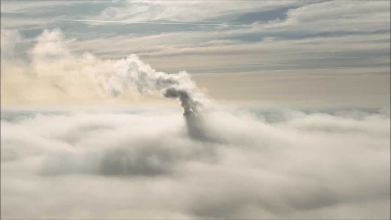 Luftfoto af cementfabriksrøg over tågeinversion.
