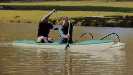 two men paddling an outrigger canoe on a lake