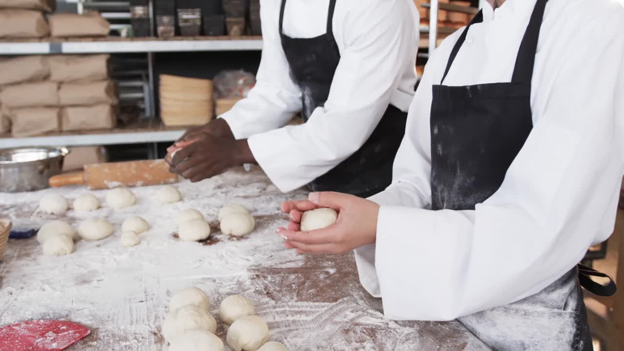 Diversi panettieri al lavoro in una panetteria, che formano panini dall'impasto al rallentatore.