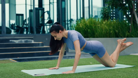 woman doing push-ups outdoors on a yoga mat