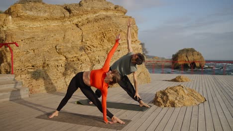 couple practicing yoga outdoors by the sea