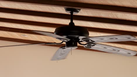 a ceiling fan rotates steadily in a wooden interior, providing a cooling effect. the lighting is warm and ambient