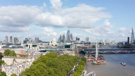 Aerial-view-of-green-trees-in-Temple-Gardens-on-bank-of-River-Thames.-Modern-office-buildings-in-background.-London,-UK