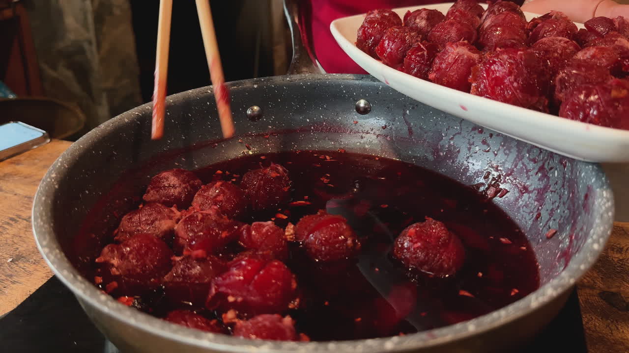 Traditional Vietnamese dish of plums served from pot using chopsticks into white plate