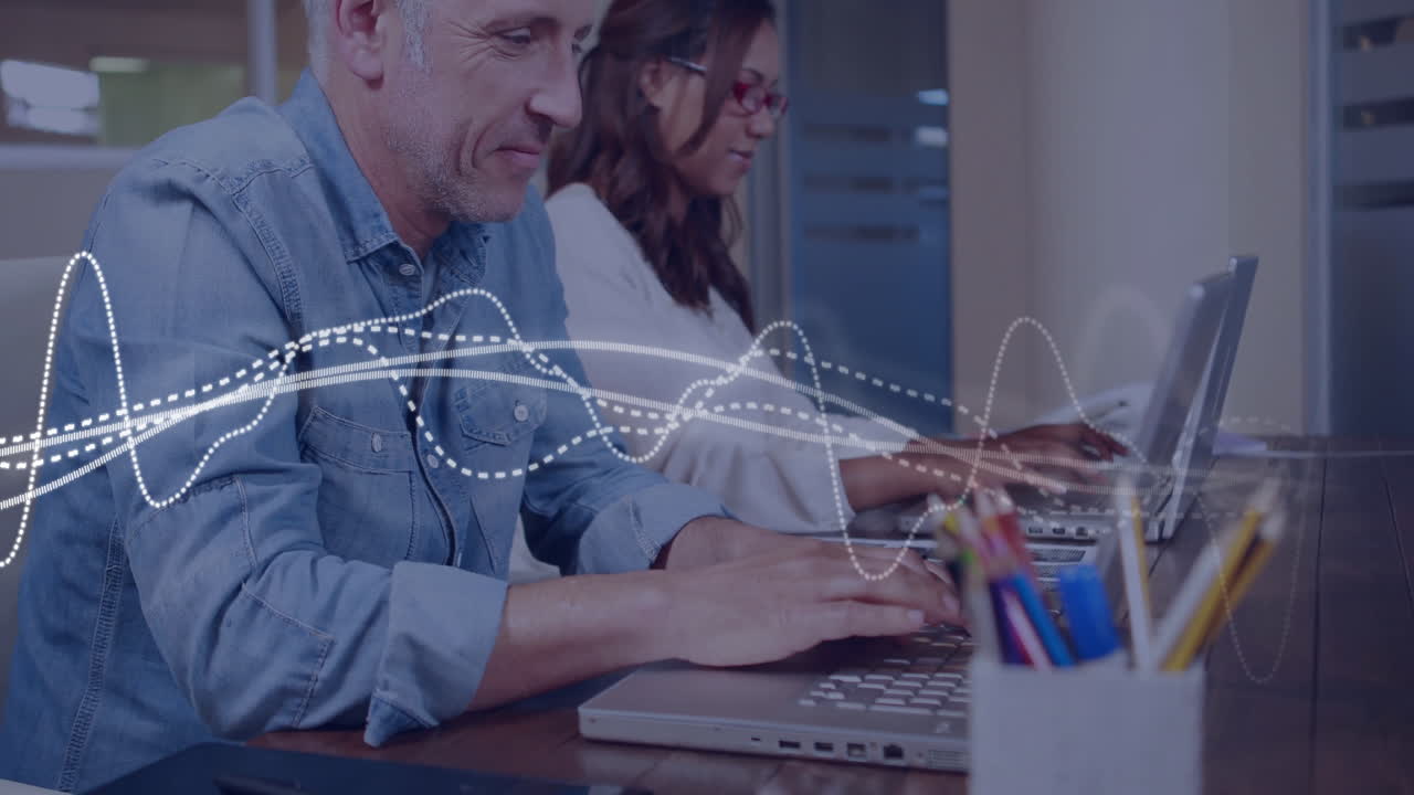 Two people working on laptops with sound wave animation overlay