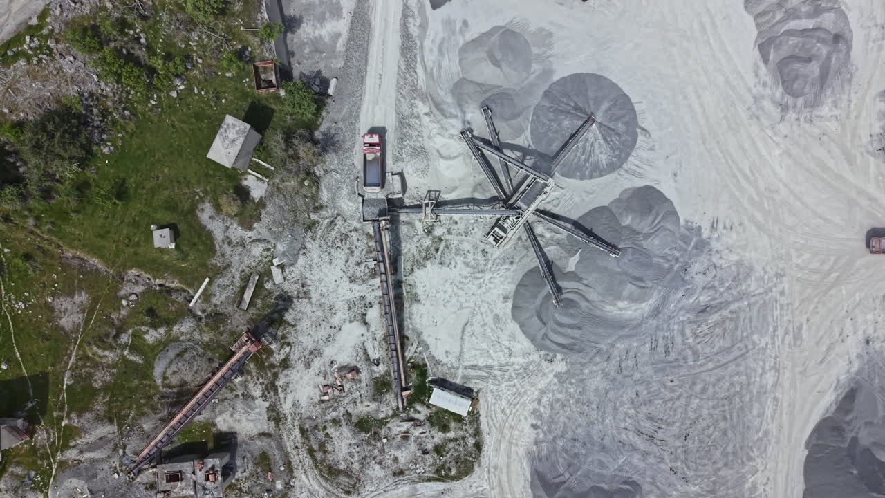 Heavy machinery operates in a quarry as trucks transport materials during daylight hours