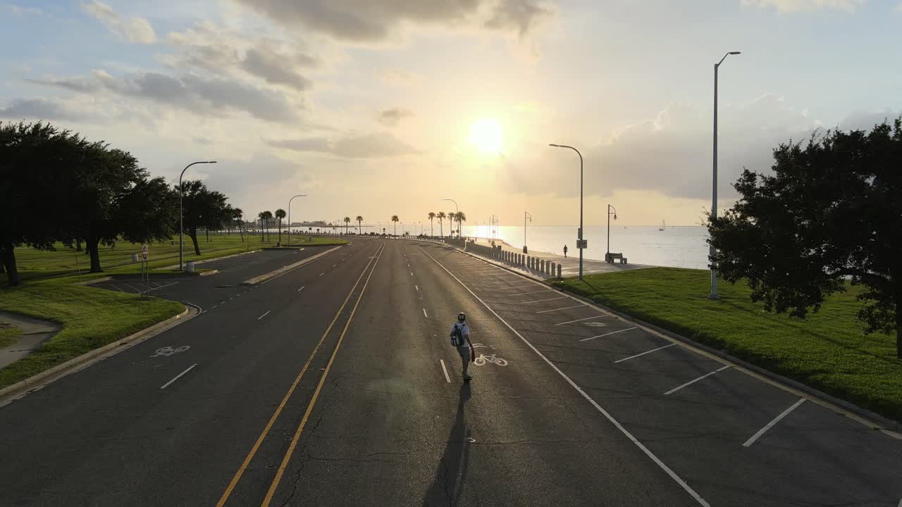 Skateboarder Ride On Electric Skateboard Leisurely Traveling At Lakeshore Drive During Sunset In New Orleans, Louisiana, USA. - aerial