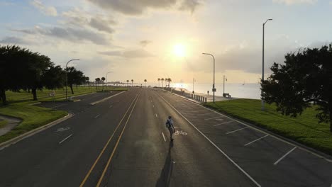 skateboarder ride on electric skateboard leisurely traveling at lakeshore drive during sunset in new orleans, louisiana, usa. - aerial