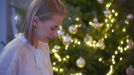 concentrated woman prepares silver christmas baubles for tree