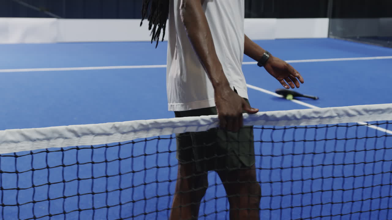 Man playing padel tennis, preparing to serve on blue court on indoor court