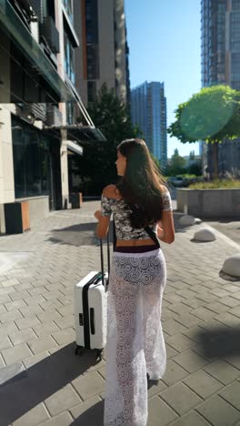 woman walking with suitcase in city street