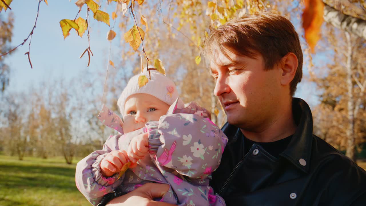 Et hjertevarmt øjeblik mellem en far og hans baby om efteråret med farverige blade i baggrunden, der fanger glæde og ømhed sammen i naturen