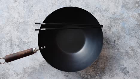 traditional empty black iron wok pan placed on stone background