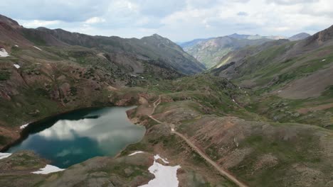 a slow side-moving drone shot of a deep blue glacial alpine lake high in the san juan mountains of colorado in the summertime