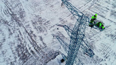 toma aérea inclinada hacia arriba del trabajador que instala un poste eléctrico en el paisaje invernal