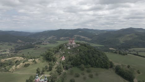 Small-chapel-on-the-top-of-the-hill-surrounded-by-mountains-in-Slovakia-during-cloudy-day