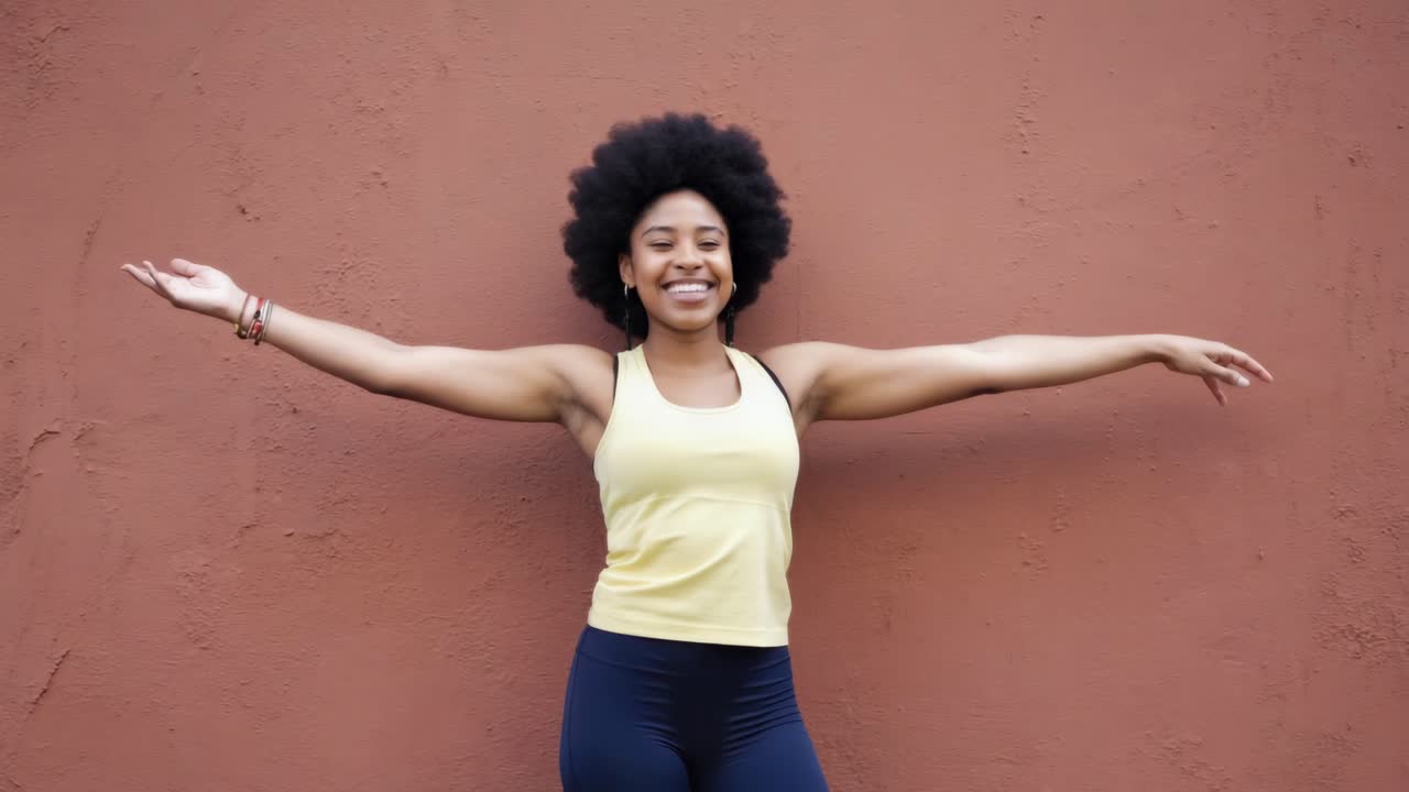 Woman stretching in wellness concept, radiating confidence with open arms and bright smile against minimalist brown background, embodying contemporary fitness lifestyle and personal empowerment