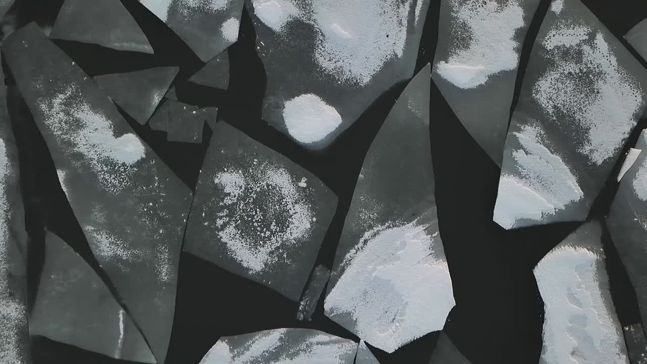 Drone shot flying over frozen lake covered in ice and snow flying passed chunks of ice