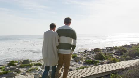 Caucasian-couple-enjoying-free-time-by-sea-on-sunny-day-walking-path