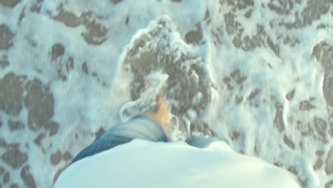 Barefoot-man-walking-on-the-beach-and-splashing-coastal-waves