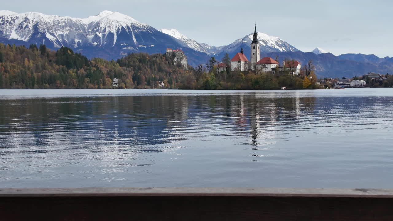 Vista mozzafiato del lago di Bled con la sua isola, la chiesa e il castello che si rivelano da dietro una ringhiera