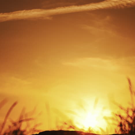 young man with helmet walking with his bicycle on the orange sky background in the evening. amazing view of a golden setting of a sun and a silhouette of a cyclist going next to his bike.
