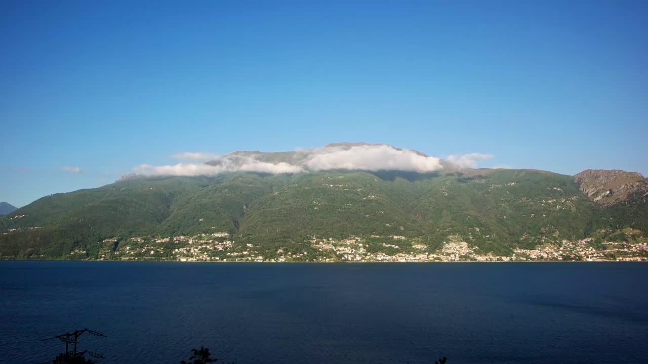 밝은 여름날에 벨레라 언덕 위에 낮은 구름의 코모 호수는 은 은 구름과 함께 깊은 파란색 호수 물이 울창한 녹색 언덕을 따라 기어가는 것처럼 보입니다.