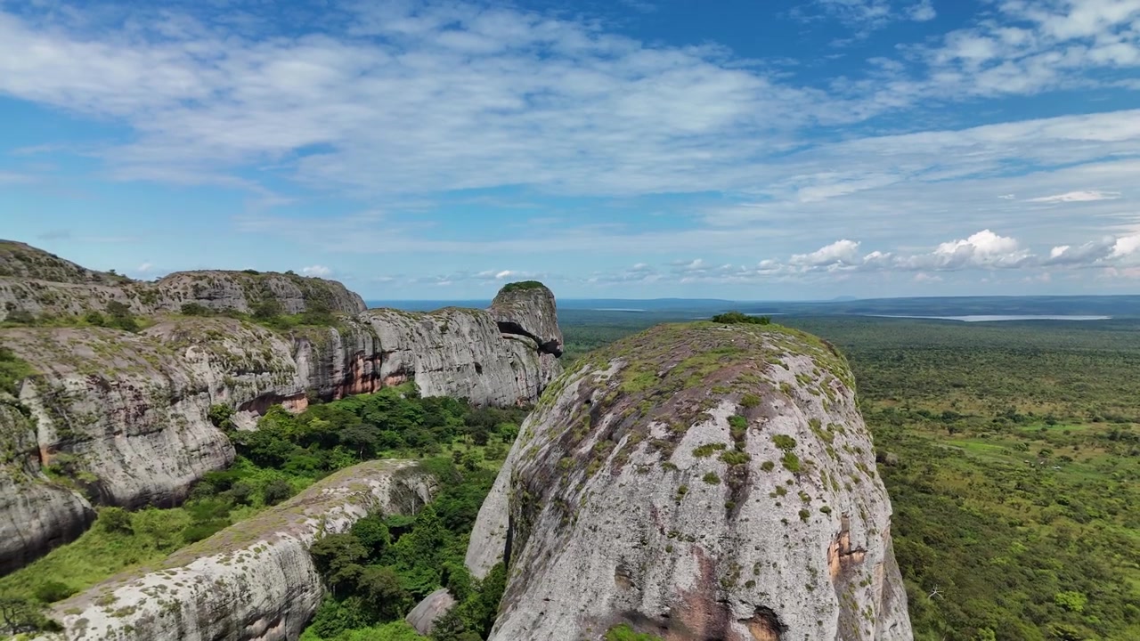 Ampia panoramica aerea dall'alto delle famose formazioni rocciose delle Pietre Nere di Pungo Andongo che si ergono sopra vaste pianure di savana verde e laghi nella provincia di Malanje, Angola, Africa Meridionale