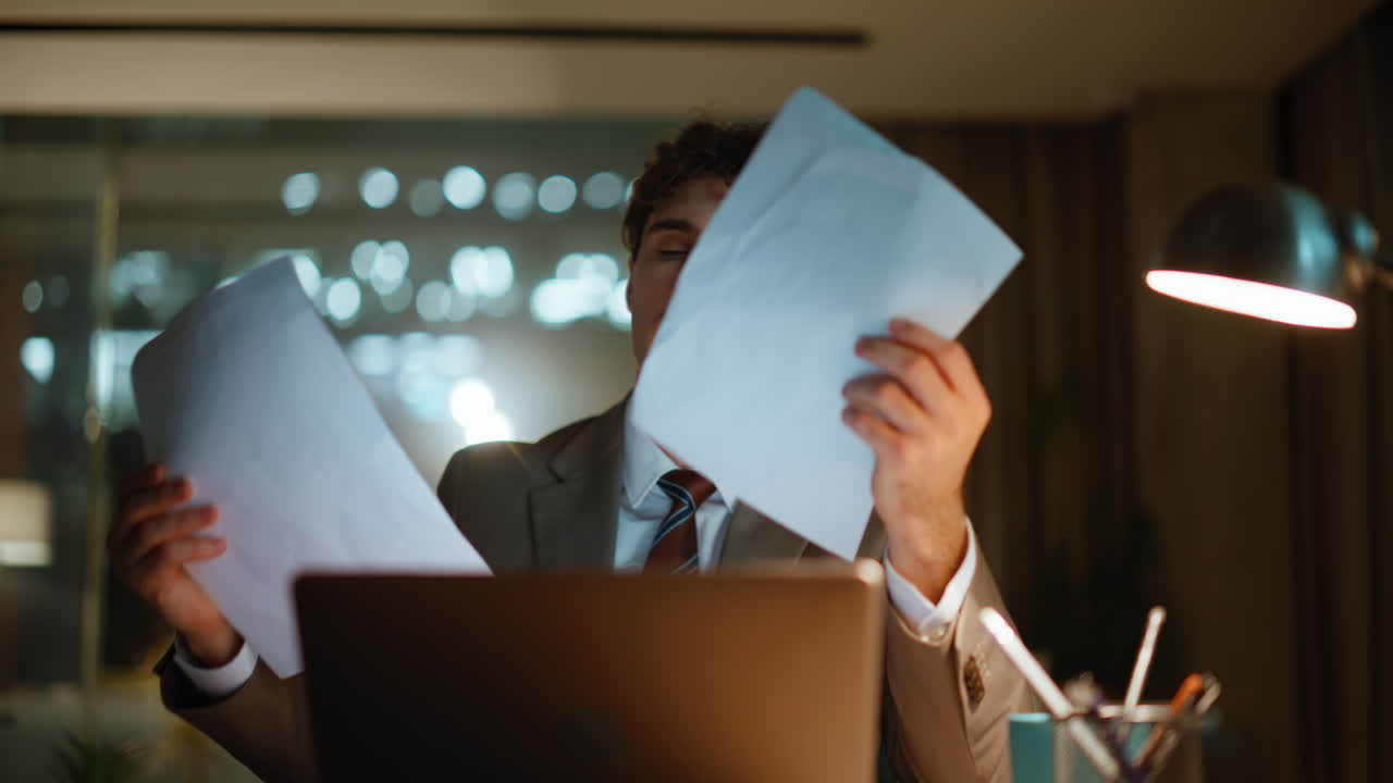 Focused man examining documentation working at night corporate workplace closeup