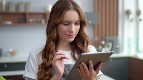 Portrait-of-woman-chef-in-kitchen.-Happy-housewife-looking-tablet-screen-at-home