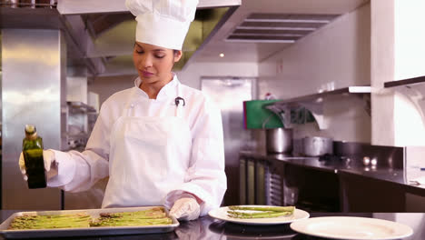 chef pouring olive oil over asparagus