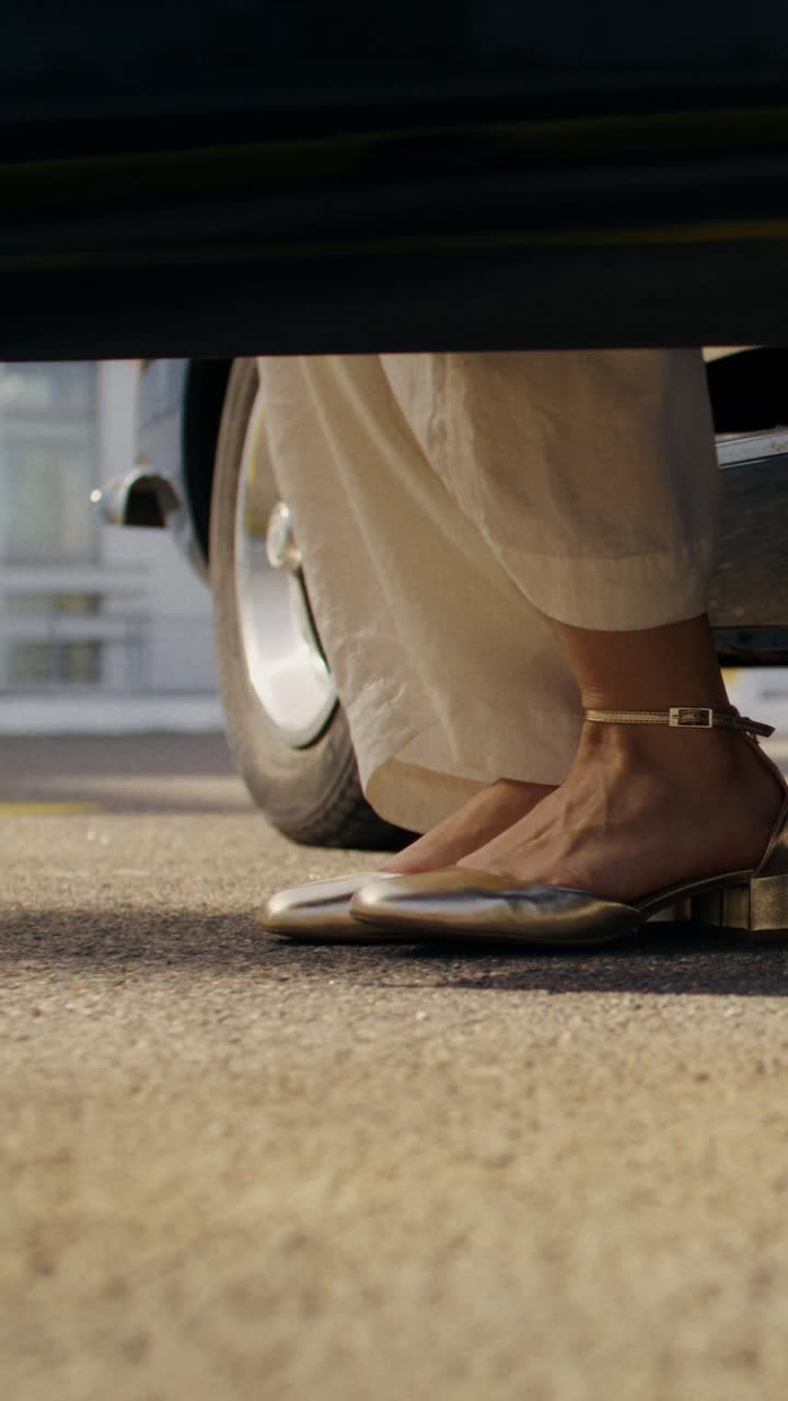 Woman's feet in gold sandals near a classic car