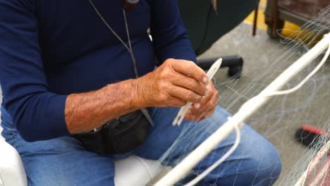 old fisherman reparing fishing net during the day