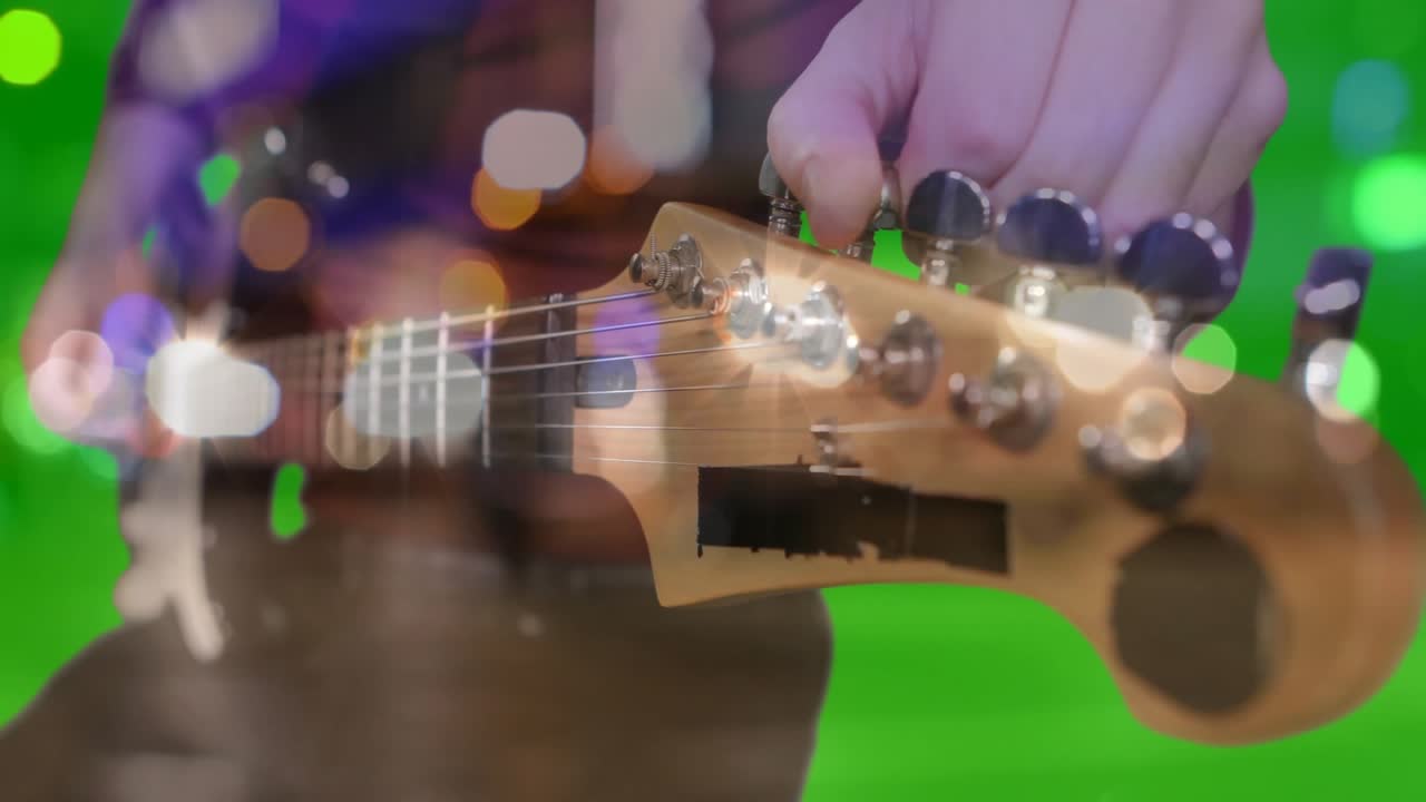 Mano maschile che regola la paletta della chitarra in uno studio musicale, con effetto bokeh e sfondo cromatico verde.