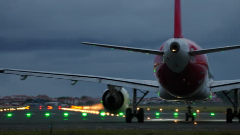airplane positioned on runway with illuminated lights in the background, capturing the essence of aviation and travel at dusk