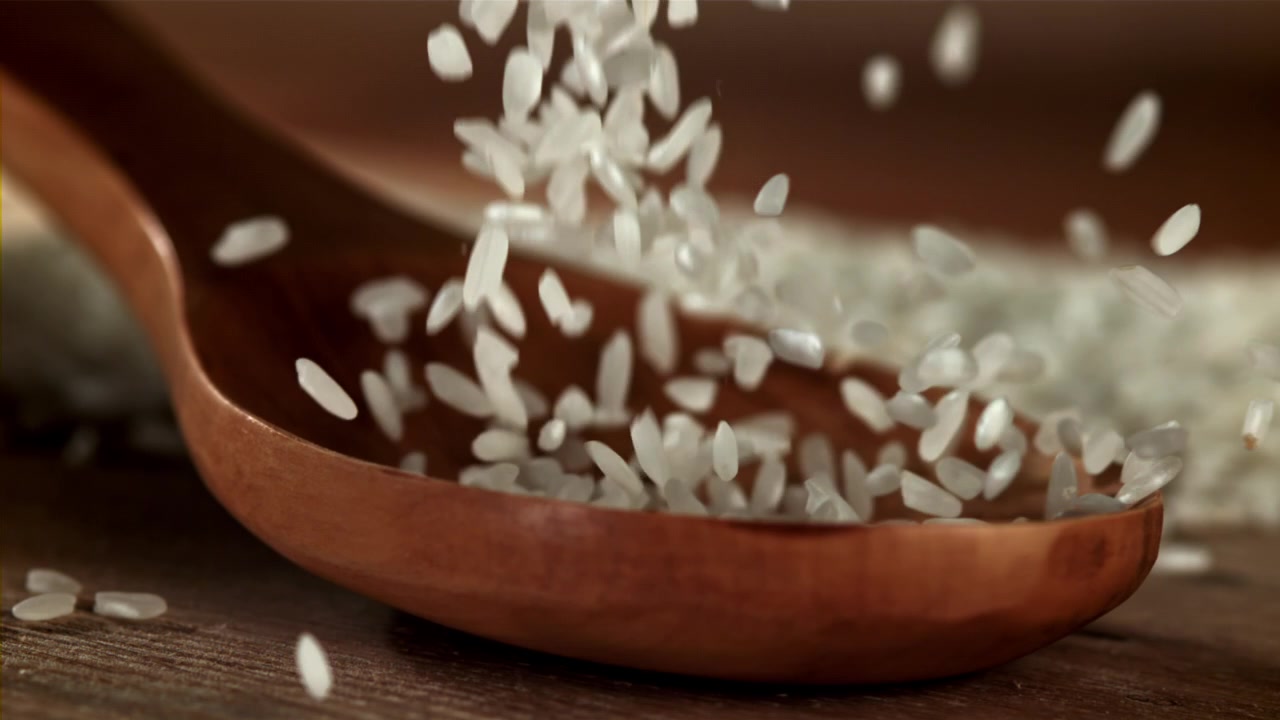 Slowmotion af hvide risgryn, der hældes ned i en træske