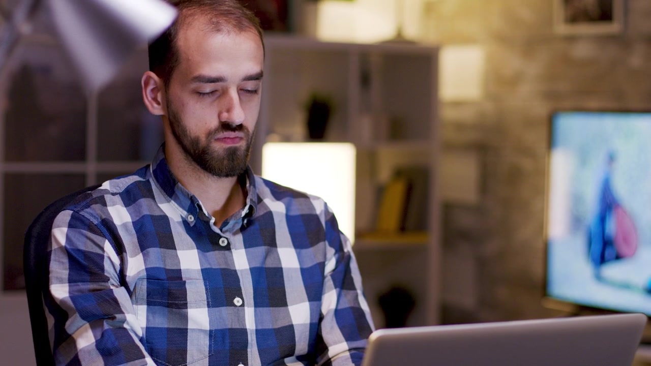 Young Man Working on Laptop in Home Office at Night