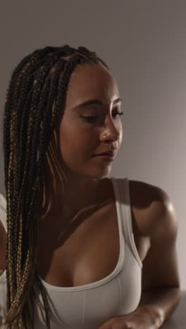 studio beauty shot of young woman with long braided hair against neutral background in profile