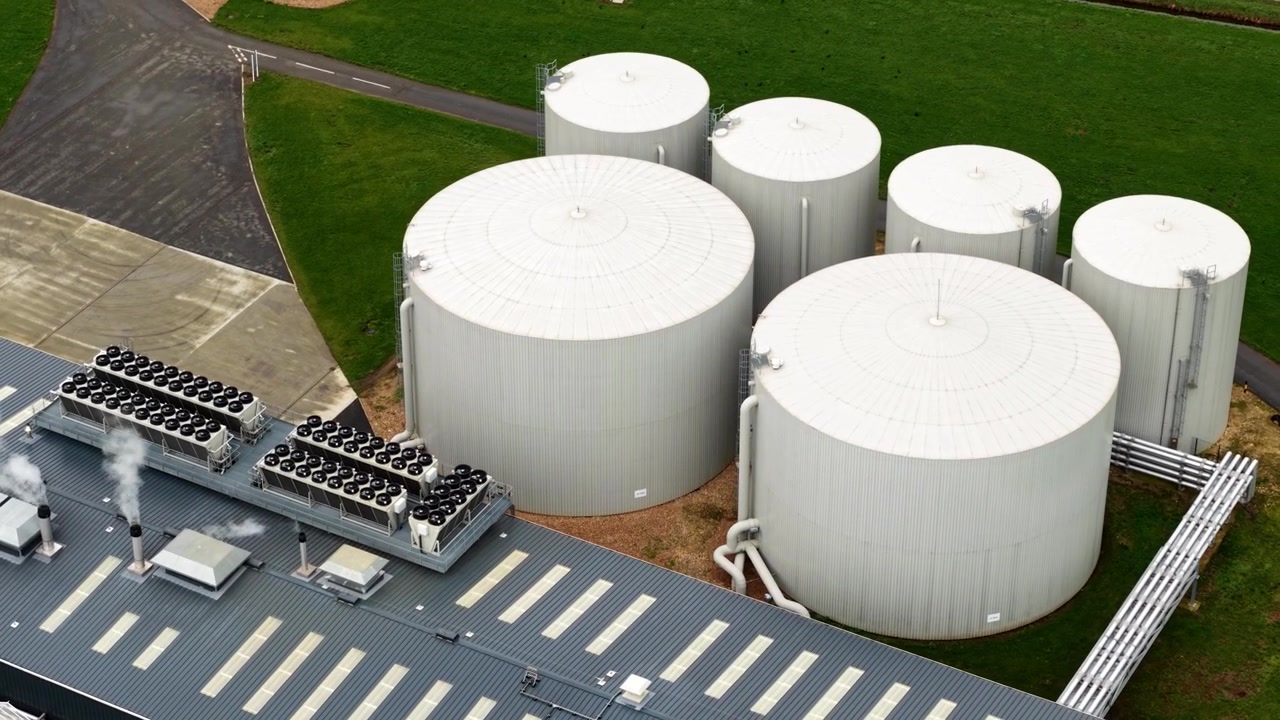Luftfoto i nærbillede fra høj vinkel, der fokuserer på det industrielle biomasseenergianlæg og lagersiloer forbundet med et kommercielt drivhusanlæg, Storbritannien